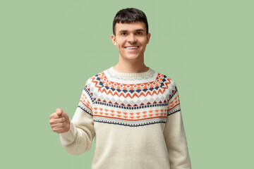 Young deaf mute man using sign language on green background