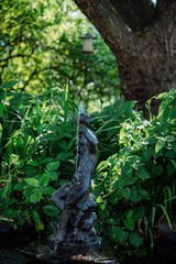 Old Statue of a little boy in green garden in the summer