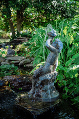Old Statue of a little boy in green garden in the summer