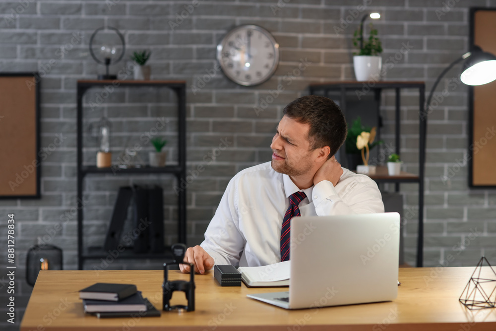 Poster Young businessman suffering from neck pain in office at night