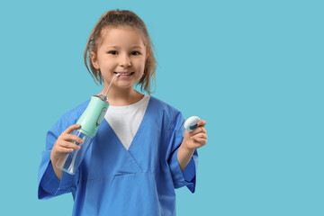 Cute little dentist with oral irrigator and dental floss on blue background
