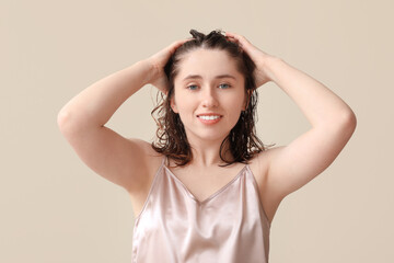 Fototapeta premium Beautiful young happy woman after washing hair on beige background