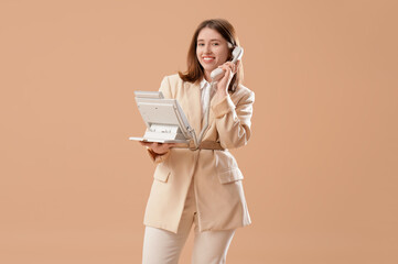 Fototapeta premium Pretty businesswoman talking on phone on beige background