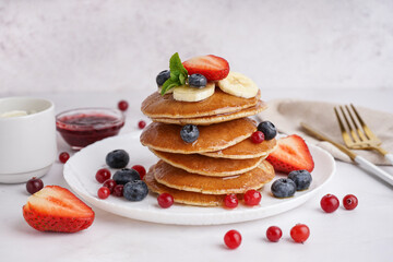 Plate with tasty pancakes, cutlery and berries on white table