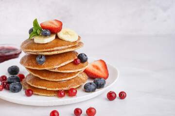 Plate with tasty pancakes, cutlery and berries on white table