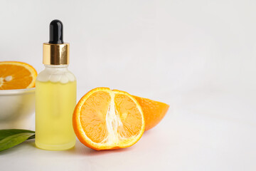 Bottle of essential oil and fresh ripe orange on light background