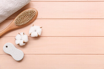 Beautiful spa composition with pumice stone, massage body brush and cotton flowers on pink wooden background