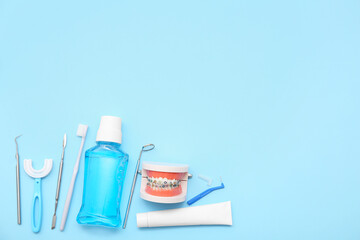 Jaw model with mouthwash, toothpaste and dental tools on blue background