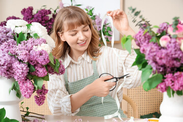 Female florist cutting ribbon for bouquet with lilacs in flower shop