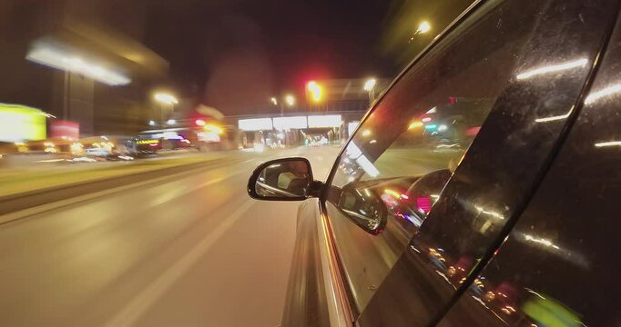 Timelapse of sport car driving fast down city road at night with driver looking in the mirror, scene with motion blur
