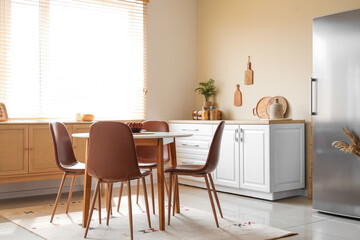 Interior of light kitchen with stylish fridge, white counter and dining table