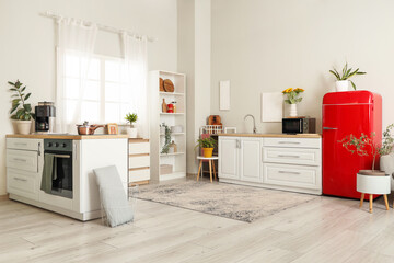 Interior of stylish kitchen with red fridge and white counters