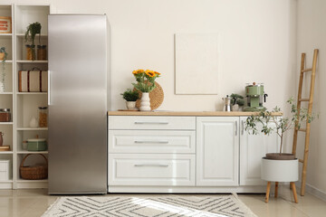 Interior of kitchen with modern fridge and white counter