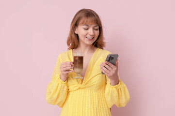 Obraz premium Happy young woman with glass of tasty iced latte and mobile phone on pink background