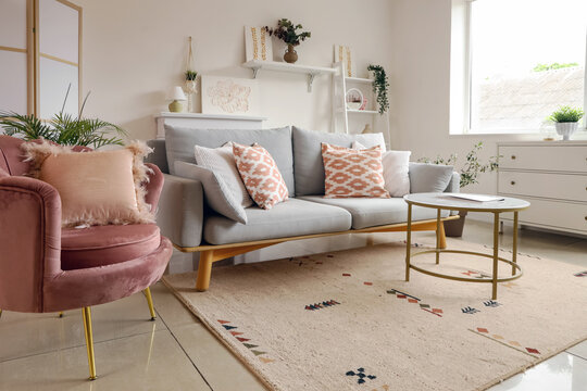Cozy sofa, armchair, coffee table and pictures in living room