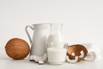 Jug, bottle and glass with tasty coconut milk on white background