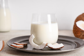 Dark plate and glass of tasty coconut milk on grunge background, closeup
