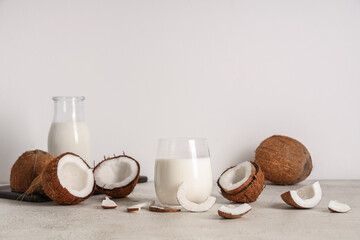 Bottle and glass of tasty coconut milk on light background
