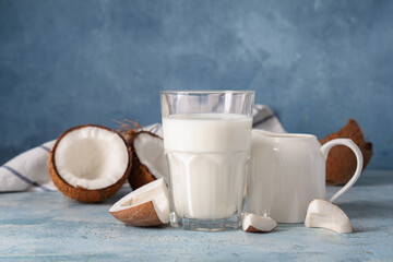 Glass and jug of tasty coconut milk on blue grunge background