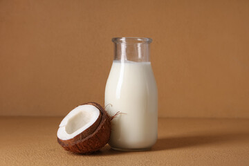 Bottle of tasty fresh coconut milk on beige background