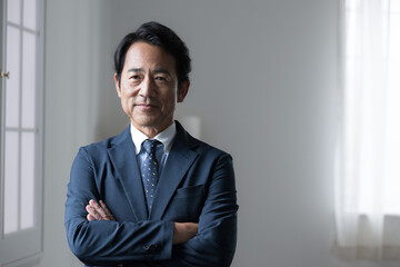 Handsome senior businessman with a serious look on his face, arms folded, managerial or executive...