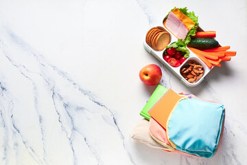Lunch box with tasty food and school supplies on white background. Top view
