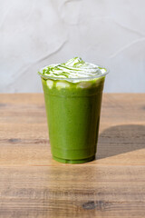 木のテーブルにプラスチックのコップにはいった抹茶フラッペ