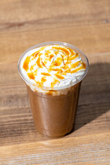 木のテーブルにプラスチックのコップにはいったキャラメルフラッペ