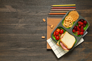 School supplies, lunch box with berries and sandwich on wooden background. Top view