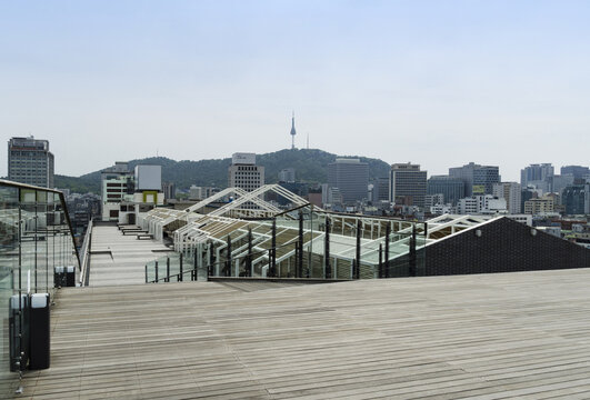 Jongno-gu, Seoul, South Korea - May 8, 2019: Summer view of wood deck and handrails on rooftop garden of Seun Shopping Center against skyscrapers and N Seoul Towe
