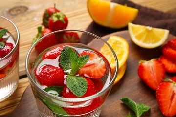 Glass of infused water with strawberries and mint on wooden background