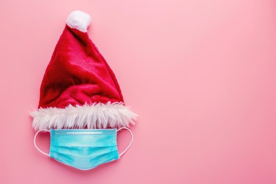 A festive combination of a Santa hat and a face mask on a bright pink background, perfect for holiday or themed events