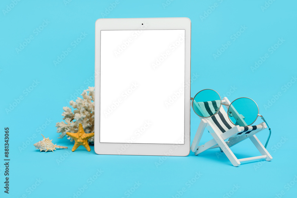 Wall mural Tablet and beach accessories with coral, mini deck chair and sunglasses on blue background