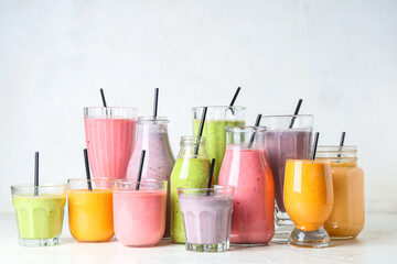 Glasses and bottles of different fresh smoothie on white background