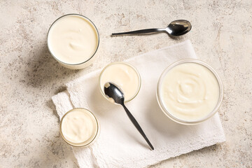Glass bowls and jar of tasty yogurt on white background