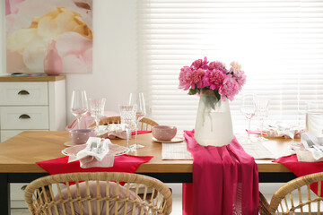 Pink peonies on table with beautiful setting and rattan chairs in dining room