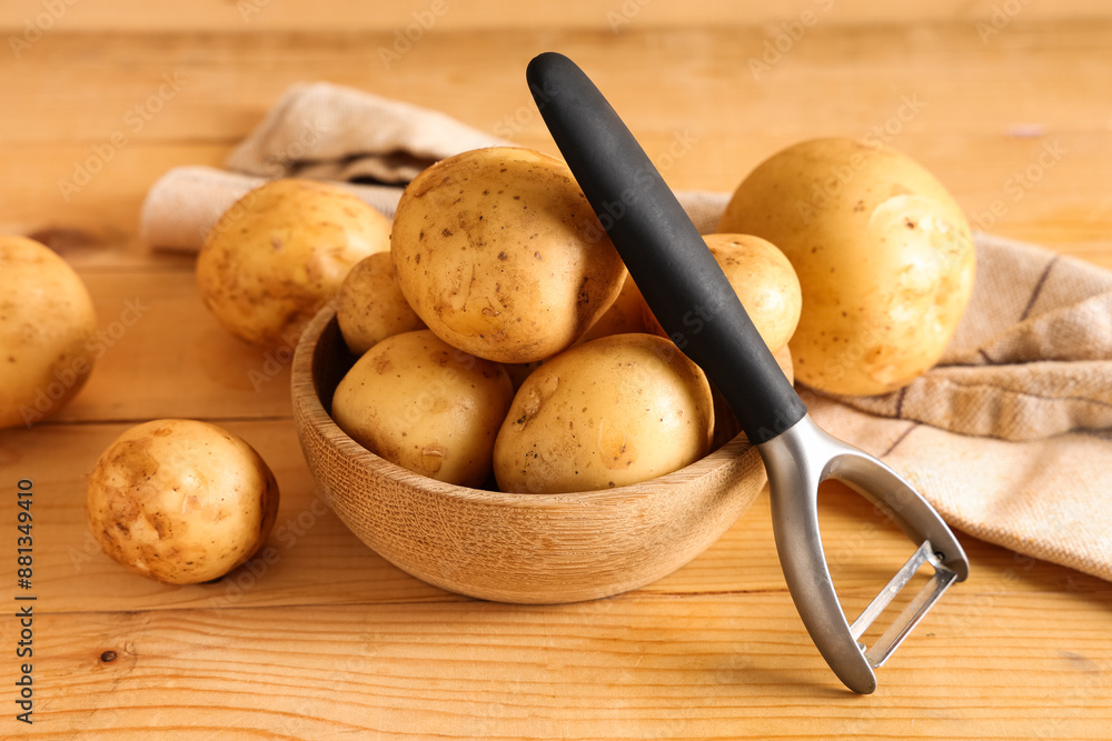 Canvas Prints bowl with raw potatoes and peeler on wooden background