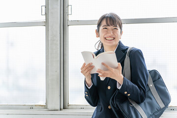 本・小説・漫画・教科書・参考書を読む笑顔の高校生
