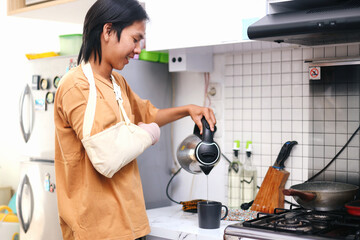 Injured Young Asian Man Pouring Hot Water To Glass At Kitchen