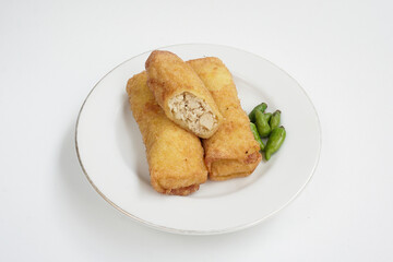 ‘Sosis solo’ or fried egg crepe with minced beef or chicken filling. This common Indonesia snack is served with chili pepper on white plate isolated in white background