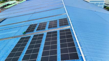 Obraz premium top aerial of engineer men inspects construction of solar cell panel or photovoltaic cell at roof top. Industrial Renewable energy of green power. factory at urban area. worker working on tower roof.