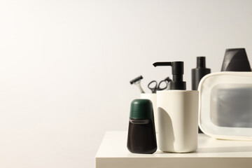 Bottles with men's cosmetics, dispenser and razors in glass on light background, space for text