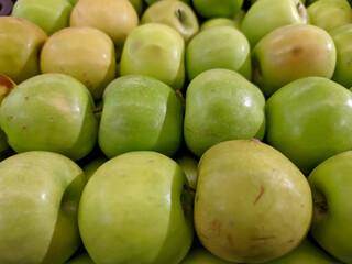 A close-up shot of a green apple reveals its vibrant, glossy skin, exuding freshness and crispness.