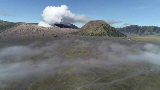 Aerial View of Mount Bromo in the Middle of a Sea of ​​Sand Bromo Tengger Semeru National Park and clouds.