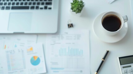 A clean and organized workspace with a laptop, coffee, charts, a calculator, and a pen.