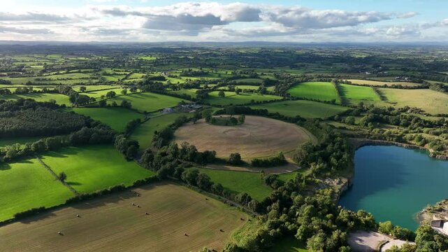 The Navan Fort, County Armagh, Northern Ireland, September 2022. Drone slowly orbits left as cloud shadow passes over cultural heritage site at top of grassy hill.