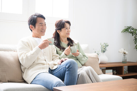Full body of a couple in their 50s relaxing in the living room Profile of a couple having a conversation