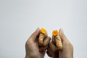 Human hands are breaking turmeric. Turmeric is a typical Indonesian spice. isolated on white background.
