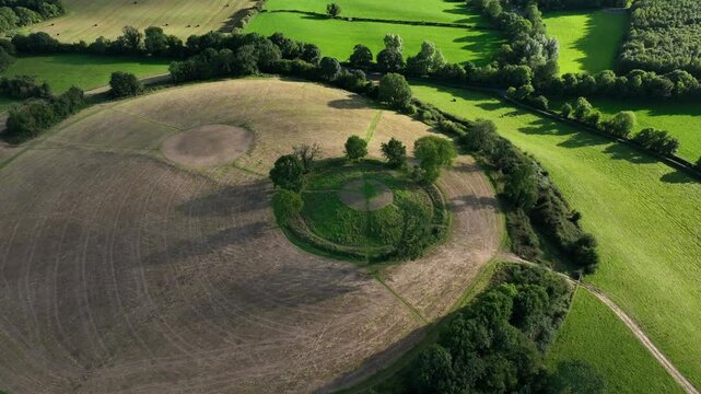 The Navan Fort, County Armagh, Northern Ireland, September 2022. Drone bird's eye view pullback slowly to establish surrounding fields around cultural heritage site on hilltop.