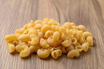 Pile of raw macaroni pasta on wooden background, Food ingredient